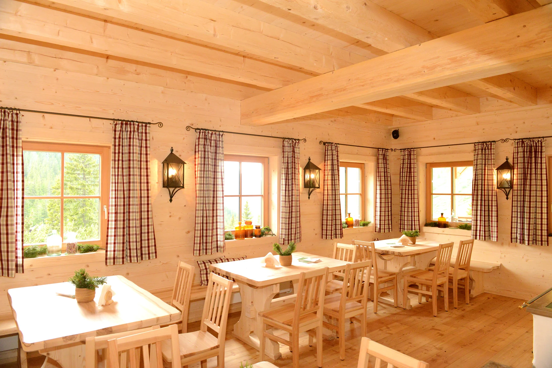 Innenraum der Latschenbrennerei mit Holztischen, Sitzbänken und sichtbarer Holzdecke