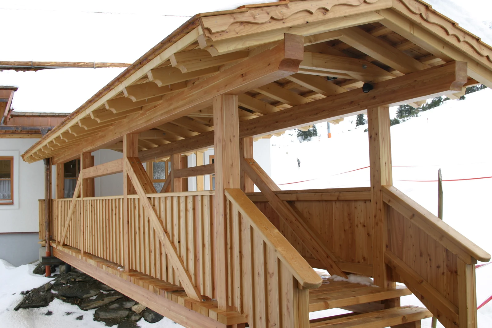 Überdachter Holzvorbau mit Balkon und Außentreppe